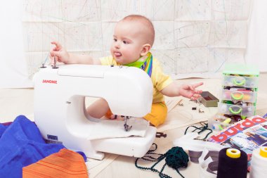 Küçük bebek bir dikiş makinesi, iplik ve makas ile giysi Tasarımcısı