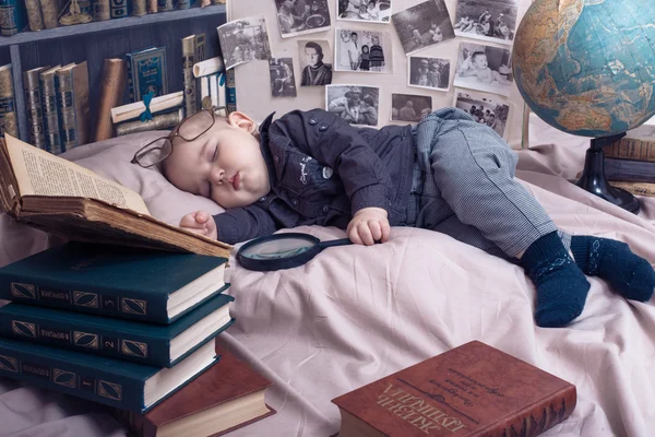 Little child scientist in glasses among the books