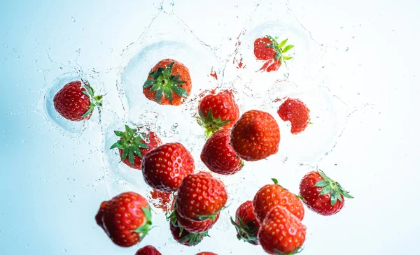 Fresas salpicando en agua clara, vista desde arriba — Foto de Stock