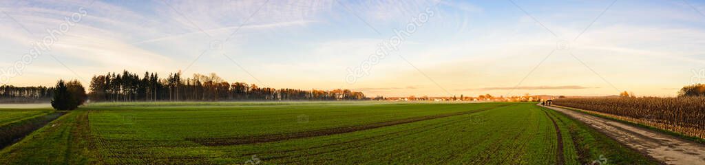 Panorama shot rural area with path between fields of leading to small Austrian village.