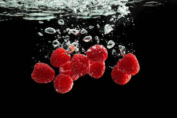 Raspberries splash into water isolated at black background — Stock Photo, Image