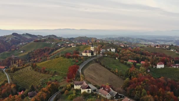 Vista aérea del pueblo austríaco Kitzeck im Sausal en el viñedo. Brote de Iglesia en la cima de la colina de la uva — Vídeo de stock