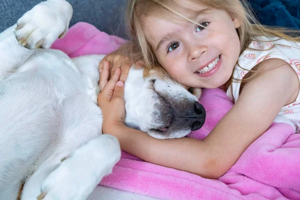 Happy Child cuddle a beagle dog best friend on sofa.