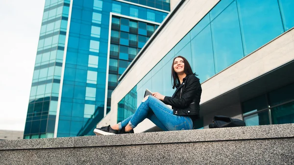 Chica sonriente con la tableta en el fondo de la ciudad —  Fotos de Stock