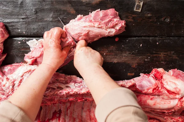 Le boucher coupe une côtelette de porc cru. fond en bois — Photo