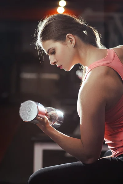 Sportliche Frau pumpt Muskeln mit Kurzhanteln auf — Stockfoto