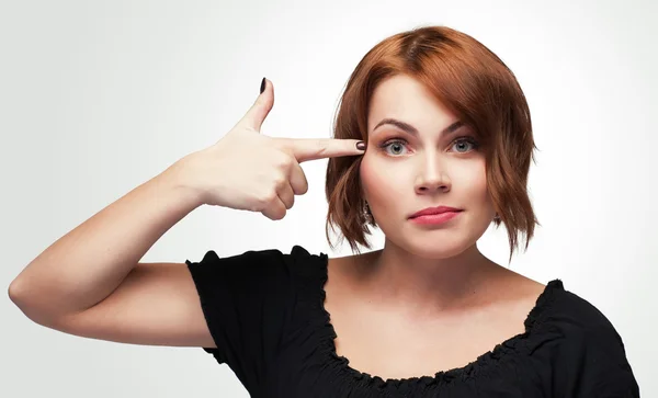 Young woman gesturing finger against her temple. — Stock Photo, Image