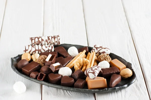 Různé čokoládové bonbony na černém plátu — Stock fotografie