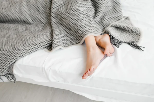 Жіночі ноги під сірою ковдрою — стокове фото