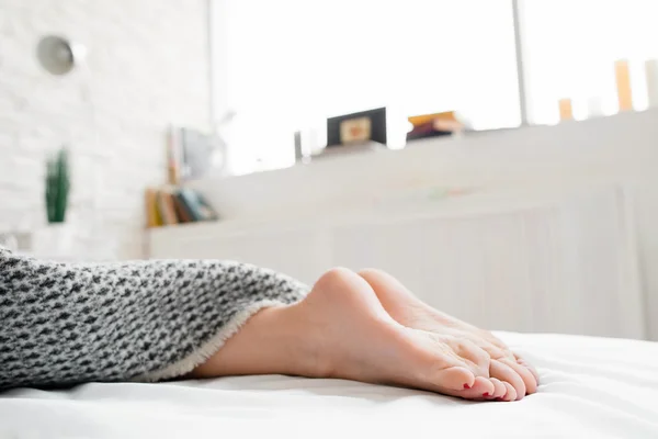 Woman feet on bed under blanket — Stock Photo, Image