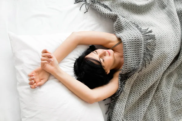 Gadis berambut coklat tidur di bawah selimut abu-abu pemandangan atas — Stok Foto