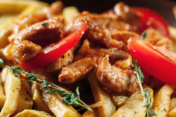 Fried potato with meat and tomato closeup