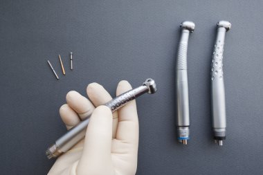 Dental handpiece in dentist hand flat lay clipart