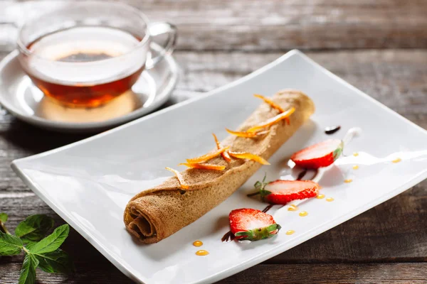Makanan penutup digulung pancake dan secangkir teh — Stok Foto