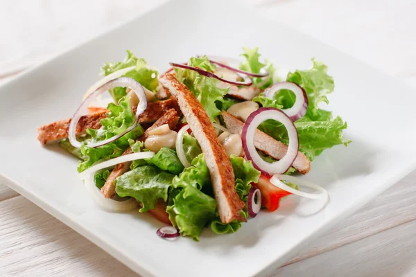 Салат с курицей и грибами на белой тарелке — стоковое фото