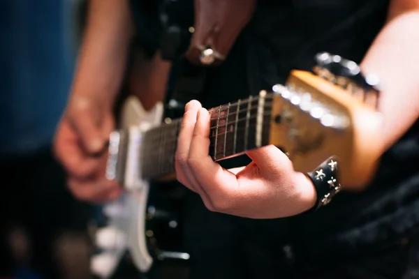 Mãos de músico na guitarra preta fundo borrado — Fotografia de Stock