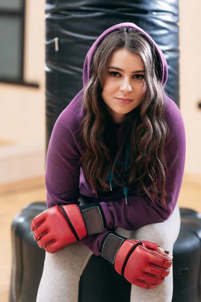 Chica joven en ropa deportiva, sentado en el saco de boxeo — Foto de Stock