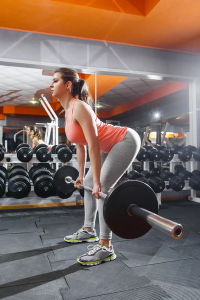 Grave atleta ragazza tiene metallo bilanciere in palestra — Foto Stock