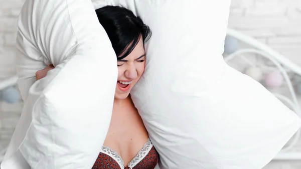 Wanita menjerit menutupi telinga dengan bantal . — Stok Foto