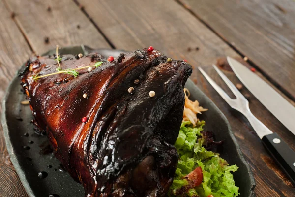 Nudillo de cerdo al horno con cubiertos en el vacío de madera — Foto de Stock