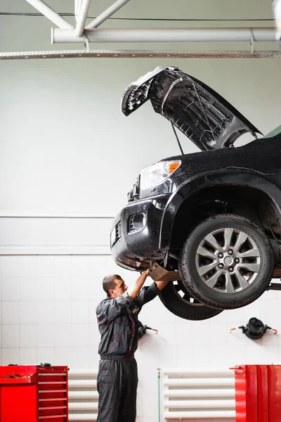 Monteur werkt onder auto in tankstation — Stockfoto