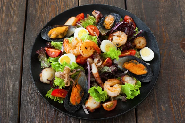 Салат с жареными морепродуктами на деревянном фоне — стоковое фото