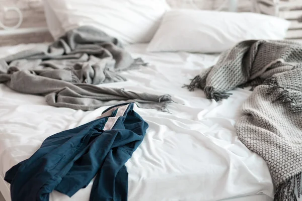 Pomarszczony koszula leżącego na zbliżenie pościelone łóżko — Zdjęcie stockowe