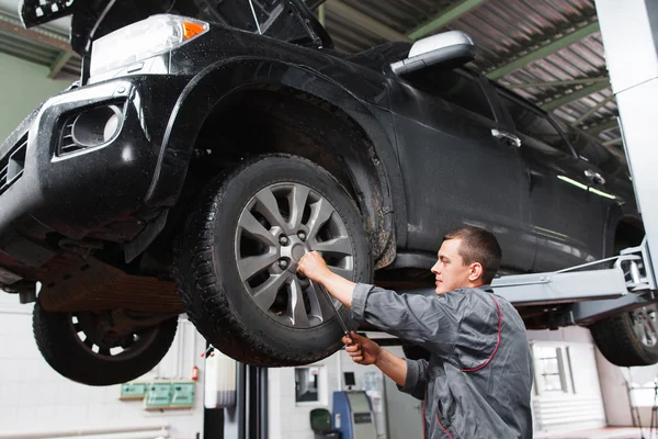 Mechanic diagnosting car wheel with screwdriver — Stock Photo, Image