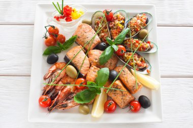 Izgara deniz ürünleri çeşitli soslu beyaz plaka üzerinde