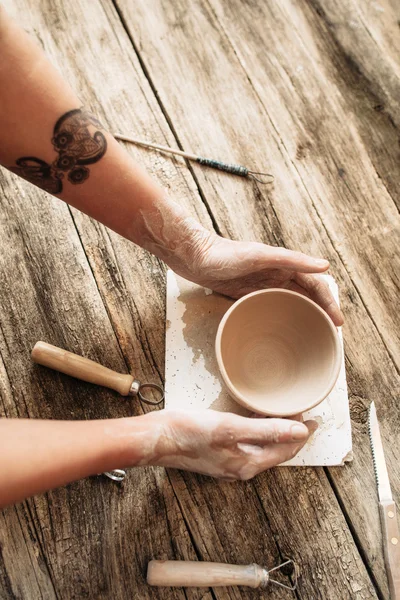 As mãos de oleiro põem o boliche de barro na mesa de madeira, closeup — Fotografia de Stock