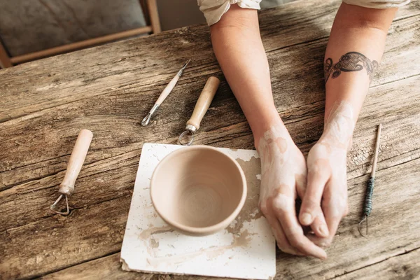 Tired potter hands near pottery on wooden table — Stock Photo, Image