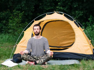Young man practicing yoga in camping