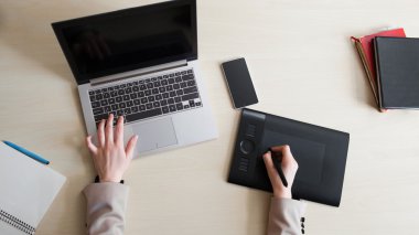 Dizüstü bilgisayar ve grafik tablet üzerinde çalışan tasarımcı