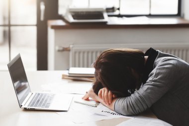 Young tired woman sleeping at office desk clipart