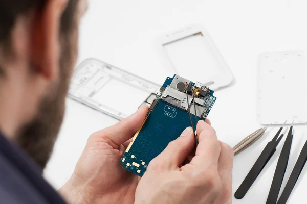 Reparador desarmando smartphone con pinzas — Foto de Stock