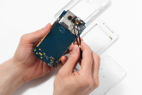 Repairman disassembling smartphone with tweezers — Stock Photo, Image