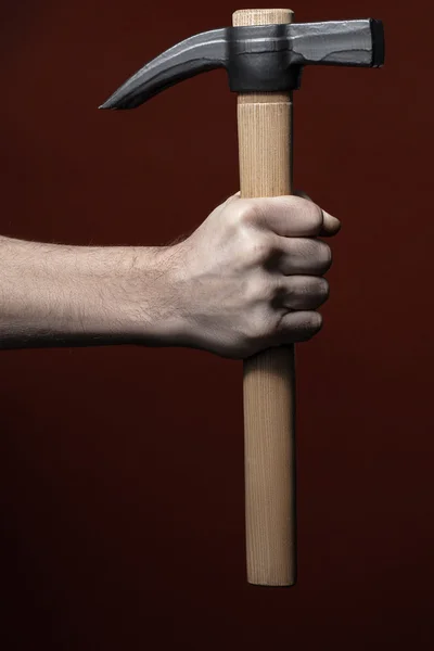 Mans mão segurando martelo no fundo vermelho — Fotografia de Stock