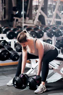 Young sexy woman doing strong exercises at gym