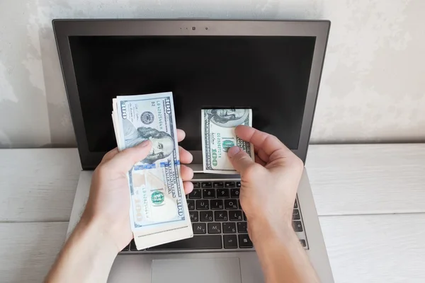 남자는 노트북 화면에 배치에서 달러 지폐를 넣어 — 스톡 사진