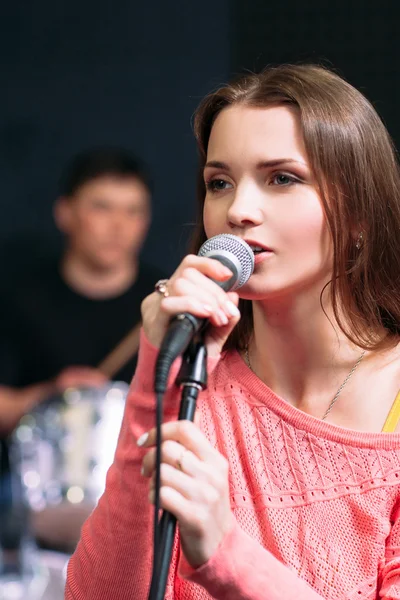 Jovem mulher atraente cantando karaoke no bar — Fotografia de Stock