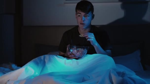 Домашній кінотеатр нічний дозвілля хлопець дивиться телевізор ліжко пізно — стокове відео