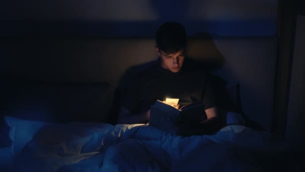 Nacht lezen home leisure guy boek telefoon flitser — Stockvideo