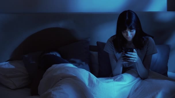 Пізно ввечері онлайн безсоння дружина використовує телефон в ліжку — стокове відео