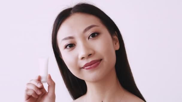 Coreeană de îngrijire a pielii asiatice femeie care arată crema facială — Videoclip de stoc
