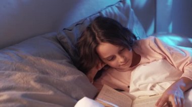 Gece masalı çocuk hobisi kız yatakta kitap okuyor.