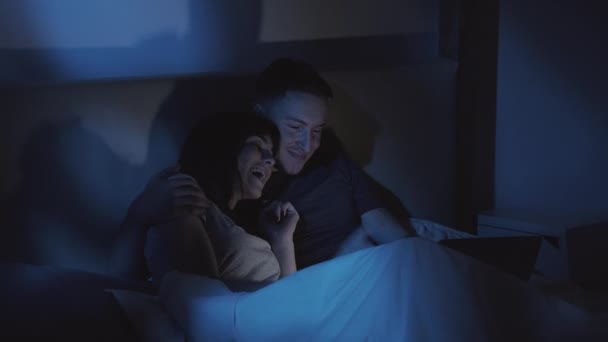 Natt på nettet handler lykkelige par bærbare i senga – stockvideo