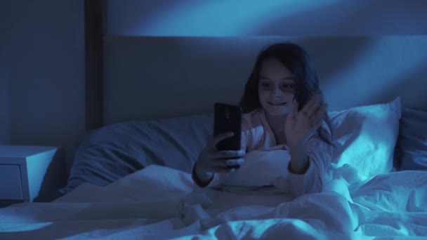 Éjszaka video hívás gyerek chat lány használja telefon az ágyban — Stock videók