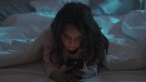 Gadget night tired little girl using phone in bed — Stock Video