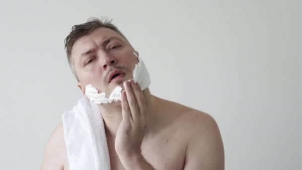 Чоловік доглядає за обличчям, застосовуючи піну для гоління — стокове відео