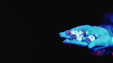 Covid-19 aşı şişeleri doktorun ellerinde eldivenlerde.